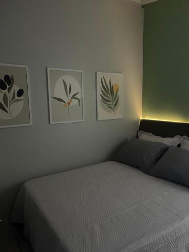 a bedroom with a bed and four pictures on the wall at Ótima suíte privada em Torres in Torres