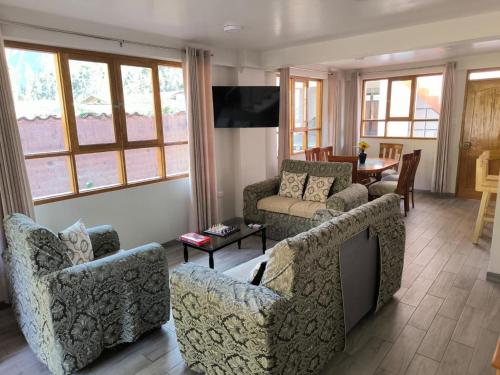 a living room with a couch and chairs and a tv at La casa del bosque CALCA in Pisac