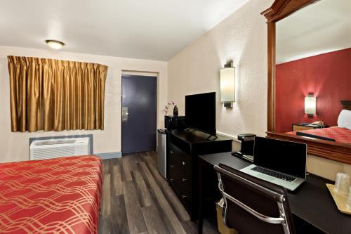 a hotel room with a bed and a desk with a laptop at Bellmawr Economy Inn Bellmawr-Philadelphia Area in Bellmawr