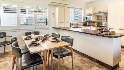 a kitchen and dining room with a table and chairs at Sharon - Pet Friendly Beach Cottage in Town - Holiday Yamba in Yamba