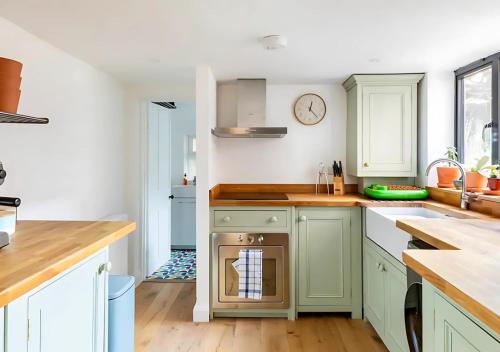a kitchen with green cabinets and a dishwasher at Stanley Road - Gorgeous Modern Flat in Oxford! in Oxford
