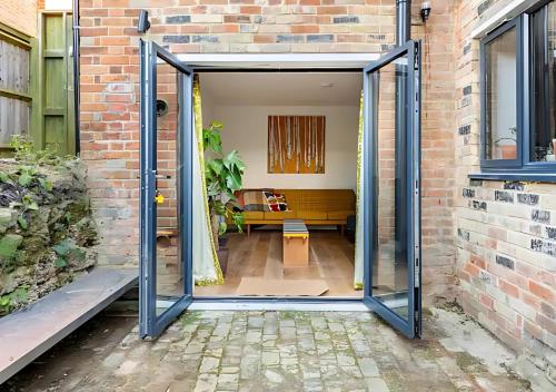 an open door leading into a room with a brick wall at Stanley Road - Gorgeous Modern Flat in Oxford! in Oxford