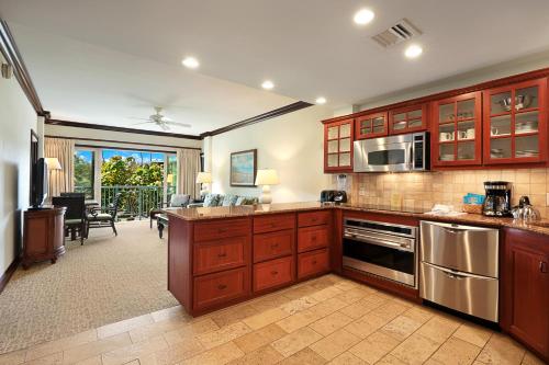 a kitchen with wooden cabinets and stainless steel appliances at Waipouli Beach Resort and Spa Kauai by OUTRIGGER in Kapaa
