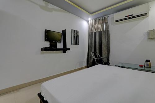a bedroom with a bed and a tv on the wall at Hotel O Sri Krishna Palace in Lucknow
