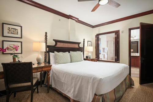 a bedroom with a bed and a desk and a chair at Waipouli Beach Resort and Spa Kauai by OUTRIGGER in Kapaa