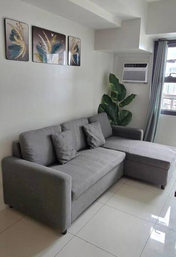 a gray couch in a living room with a plant at 1BR T2 with Balcony Panoramic View at Horizons 101 in Cebu City