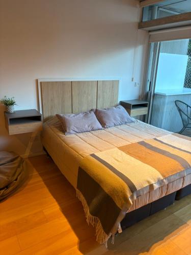 Un dormitorio con una cama grande con cabecero de madera. en Apart Soler con balcon, en Buenos Aires