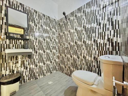 Un baño con inodoro y pared de azulejos. en Laetitia Belle Vue, en Abiyán