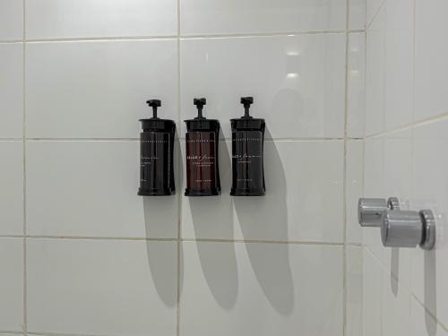 three black bottles on a tiled wall in a bathroom at Suíte Pátio Paulista 1404 in Sao Paulo