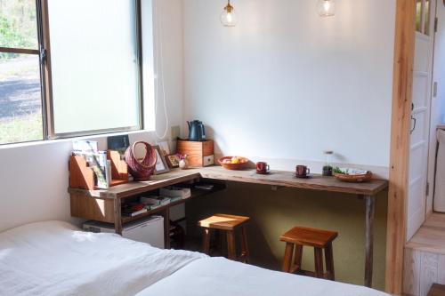 a desk in a bedroom with a bed and a window at 熊野ギャラリー のこのこ in Tanabe