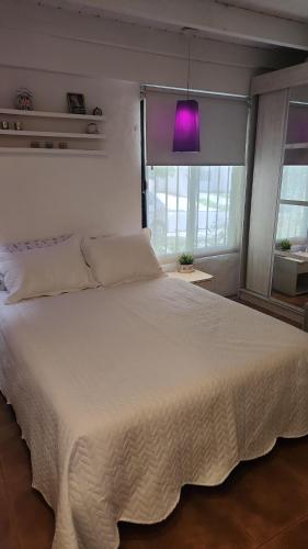 a bedroom with a large white bed with a purple light at Aire de campo en la ciudad in San Fernando del Valle de Catamarca