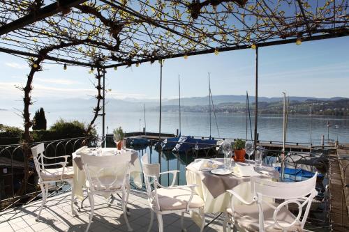 a patio with tables and chairs and a view of the water at Hotel Hirschen am See in Meilen