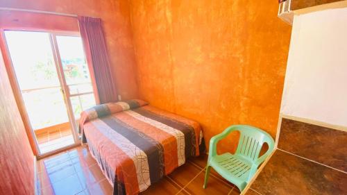 a bedroom with a bed and a chair and a window at Bungalows El Rincon de La Riviera in Rincon de Guayabitos