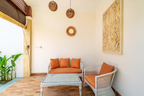 an orange chair and a table in a room at Kamaratih Villas by Maheswara in Legian