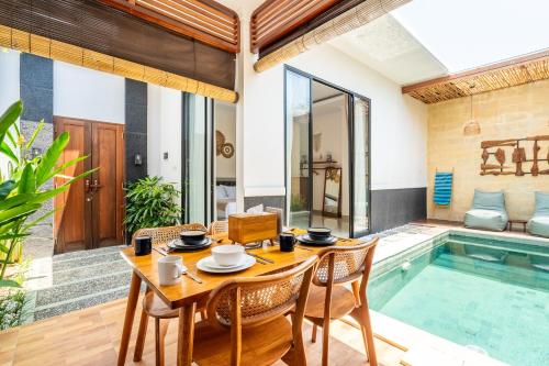a dining room with a table and chairs next to a swimming pool at Kamaratih Villas by Maheswara in Legian