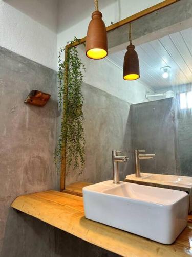 a bathroom with a sink and two lights at Casinhas da Serena in Caraíva