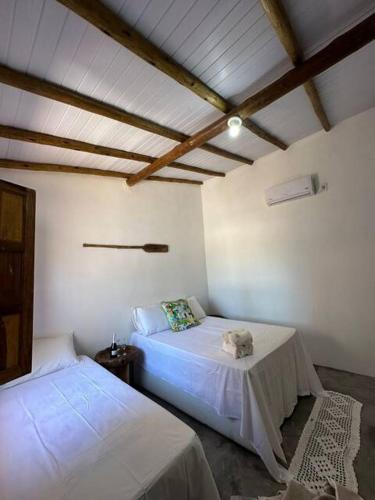 a bedroom with two beds and a ceiling with beams at Casinhas da Serena in Caraíva