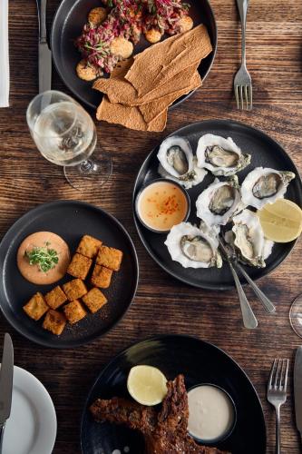 a wooden table topped with plates of food with oysters at Stillwater Seven in Launceston