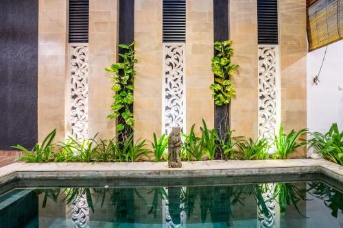 a swimming pool in front of a building with a fountain at Kamaratih Villas by Maheswara in Legian