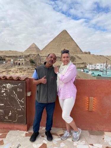 a man and a woman standing in front of the pyramids at Energy Of Pyramid Hotel in Cairo