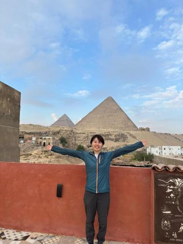 a woman standing on a wall in front of pyramids at Energy Of Pyramid Hotel in Cairo