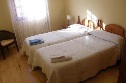 a bedroom with two beds with white sheets and a window at Casa Rural Baco in Baños de Valdearados