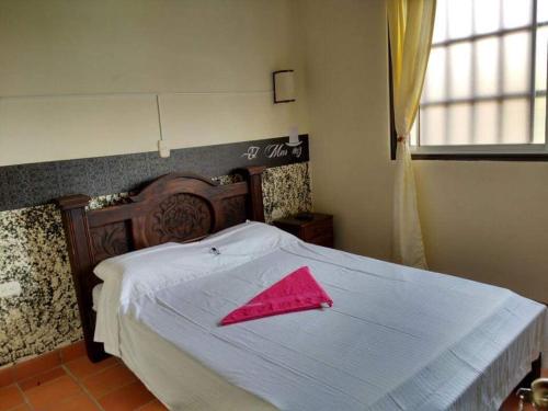 サン・ヒルにあるCasa HOTEL EL MARQUEZの白いベッドとピンクのナプキンが置かれた寝室