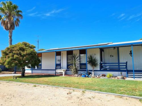 a building with a palm tree in front of it at Lil Blue Beach House in Port Hughes