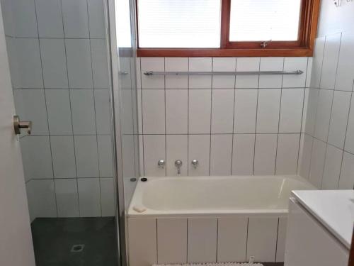 a white bathroom with a tub and a window at Lil Blue Beach House in Port Hughes