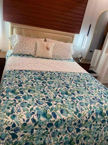 a large bed with a floral bedspread and pillows at Staycation San Jose Del Monte City in Santo Cristo