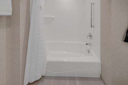 a white bath tub with a shower curtain in a bathroom at Holiday Inn Express & Suites Fort Walton Beach - Eglin Area by IHG in Fort Walton Beach