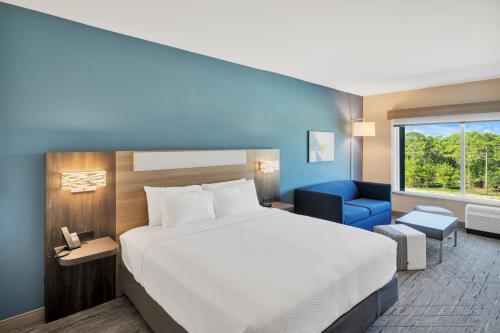a hotel room with a bed and a blue chair at Holiday Inn Express & Suites Fort Walton Beach - Eglin Area by IHG in Fort Walton Beach