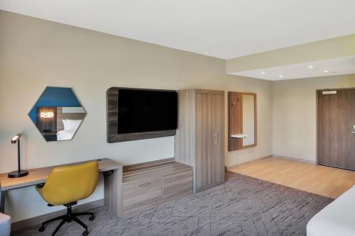 a room with a desk and a tv and a chair at Holiday Inn Express & Suites Fort Walton Beach - Eglin Area by IHG in Fort Walton Beach