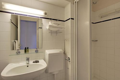 een witte badkamer met een wastafel en een douche bij Les Lilas Serviced Apartments in Les Lilas