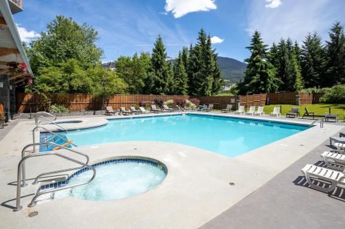 a large swimming pool with chairs around it at Newly Renovated KING BED STUDIO in the Village in Whistler