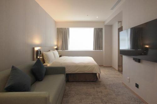a hotel room with a bed and a couch at Tango Inn Taipei Kaifong in Taipei