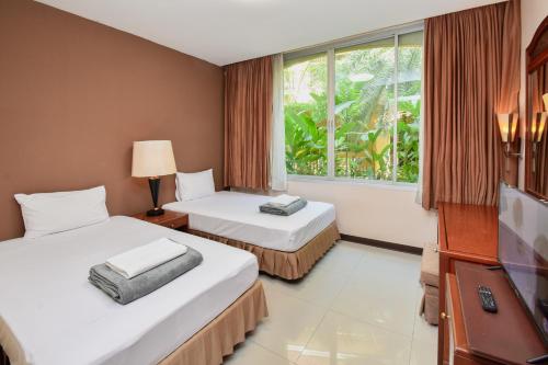 a hotel room with two beds and a window at Piman Garden Boutique Hotel in Khon Kaen