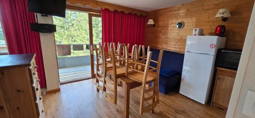 une cuisine avec une table, des chaises et un réfrigérateur dans l'établissement Appartement au pied des pistes et du park nordique, à Chamrousse
