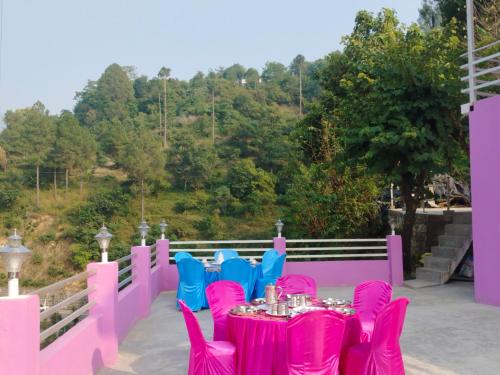 una mesa con sillas rosas y azules en el balcón en Matali HOMESTAY, en Tehri-Garhwāl