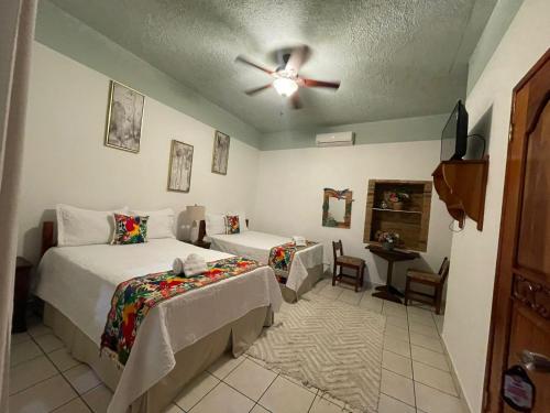 a bedroom with two beds and a ceiling fan at Hotel Itzae in Copan Ruinas