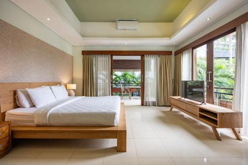 Un dormitorio con una cama y un televisor. en Cove The Ricks Villa, en Canggu