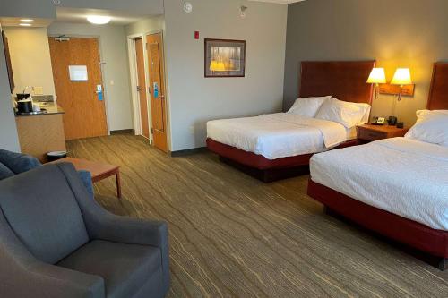 a hotel room with two beds and a chair at SouthShore Hotel on Lake Bemidji, Trademark Coll by Wyndham in Bemidji