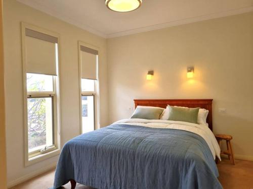 a bedroom with a large bed with two windows at Tidal Life in Wool Bay