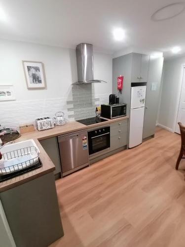 a kitchen with stainless steel appliances and wooden floors at Maunder Cottage Aldinga Township in Aldinga