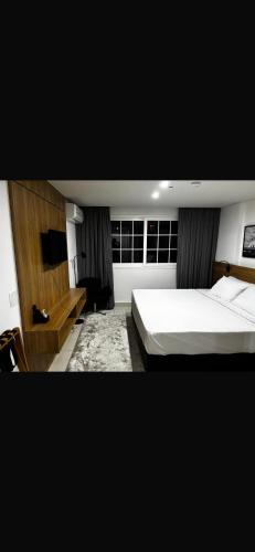 a bedroom with a large bed and a desk at Granja Brasil Flat Itaipava in Araras Petropolis