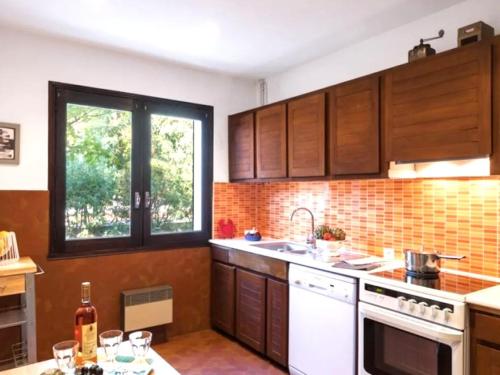 une cuisine avec des armoires en bois, un évier et une fenêtre dans l'établissement Villa paisible avec piscine chauffée et Wi-Fi - FR-1-736-50, à Lège-Cap-Ferret