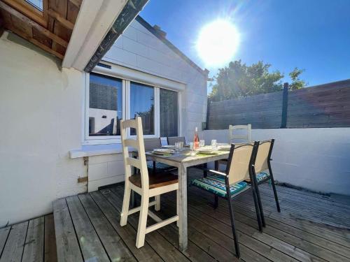 une table et des chaises assises sur une terrasse en bois dans l'établissement Maison moderne à Plouhinec avec jardin clos, Wifi, animaux admis, proche plages - FR-1-479-181, à Plouhinec