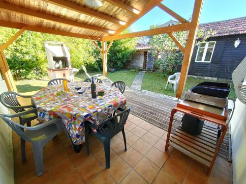 un patio avec une table, des chaises et un barbecue dans l'établissement Charmante villa à Petit-Piquey avec Jardin et WIFI, Proche Commodités - FR-1-736-49, à Lège-Cap-Ferret