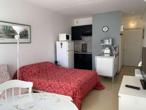 une chambre d'hôtel avec un lit rouge et une cuisine dans l'établissement Studio confortable avec balcon et WIFI à Balaruc-les-Bains - FR-1-553-281, à Balaruc-les-Bains