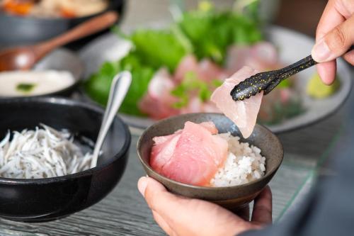 a person eating food from a bowl of rice at Hotel JAL City Haneda Tokyo in Tokyo